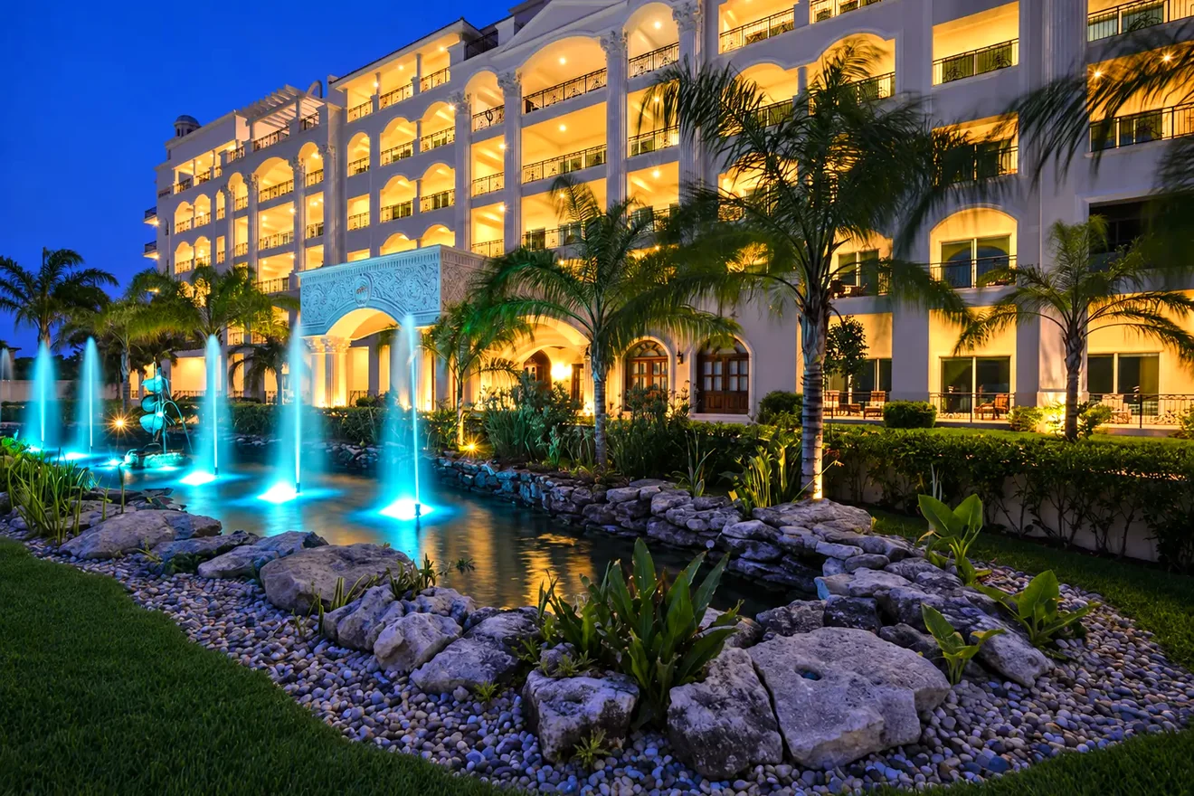 The Landmark of Cozumel at dusk with glowing fountains in front of the building