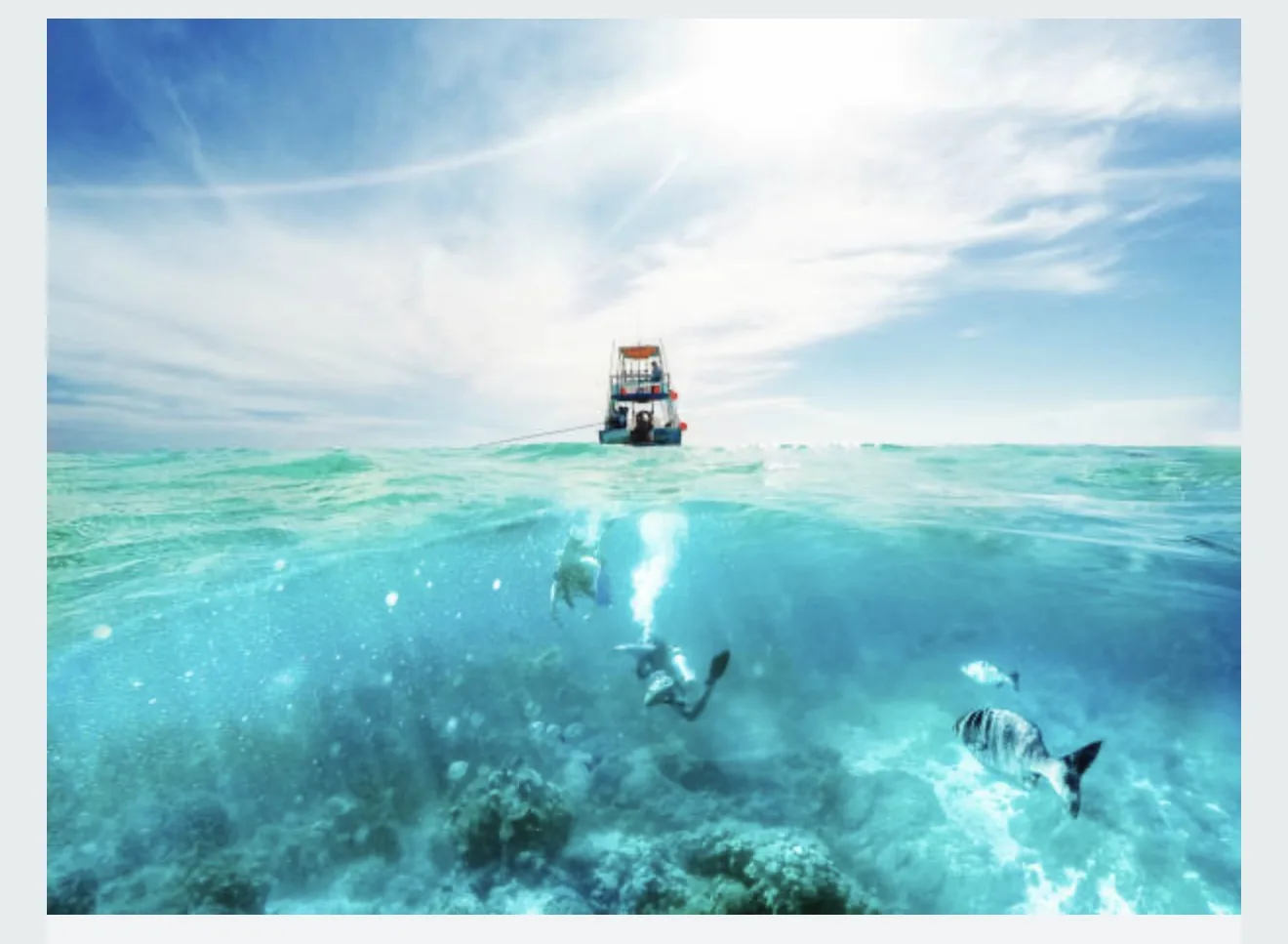 Split-level view of a snorkeler underwater with a dive boat at the surface, Cozumel